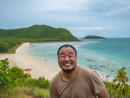 Asian fatty backpacker stand on view point on top of the island with idyllice beach ocean and blue sky and smile like crazy in vacation time,Samae San Island chonburi thailand,summer conceptの写真素材