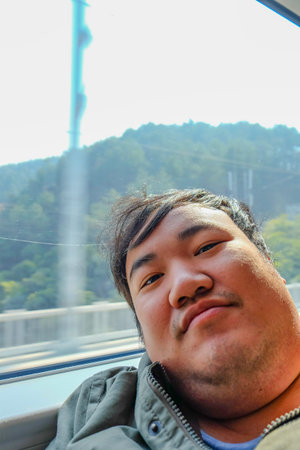 Asian Fat traveler selfie himself on the high speed train from yiwu city to shanghai city in china