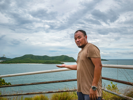 Asian Fat traveler stand on viewpoint with tropical idyllic ocean  and white cloud sky in vacation time,Chonburi thailand,Holiday conceptの写真素材
