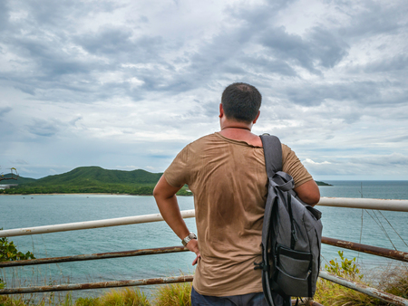 Asian Fat Backpacker stand on viewpoint with tropical idyllic ocean  and white cloud sky in vacation time,Chonburi thailand,Holiday conceptの写真素材