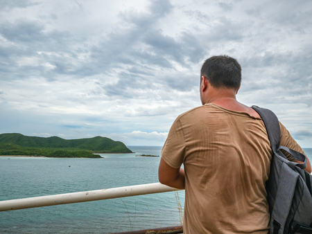 Asian Fat Backpacker stand on viewpoint with tropical idyllic ocean  and white cloud sky in vacation time,Chonburi thailand,Holiday conceptの写真素材