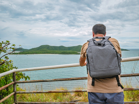 Asian Fat Backpacker stand on viewpoint with tropical idyllic ocean  and white cloud sky in vacation time,Chonburi thailand,Holiday conceptの写真素材
