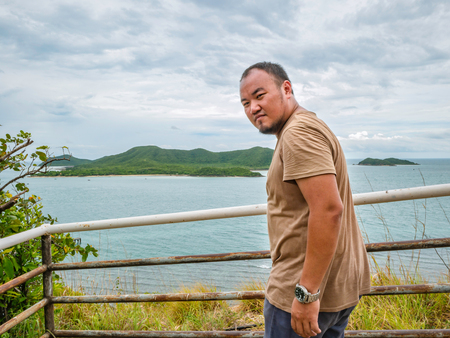 Asian Fat traveler stand on viewpoint with tropical idyllic ocean  and white cloud sky in vacation time,Chonburi thailand,Holiday conceptの写真素材