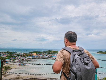 Asisn Fat Backpacker stand on top of  Khao Ma Jor Pier  with Idyllic ocean beautiful white cloud endless horizon and Fishman townscape in vacation time,chonburi thailand,holiday conceptの写真素材