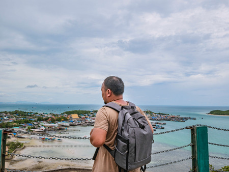 Asisn Fat Backpacker stand on top of  Khao Ma Jor Pier  with Idyllic ocean beautiful white cloud endless horizon and Fishman townscape in vacation time,chonburi thailand,holiday conceptの写真素材