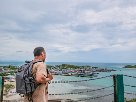 Asisn Fat Backpacker stand on top of  Khao Ma Jor Pier  with Idyllic ocean beautiful white cloud endless horizon and Fishman townscape in vacation time,chonburi thailand,holiday conceptの写真素材