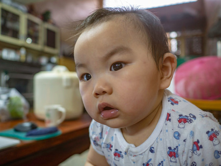 Cutie handsome asian Boy baby make a serious face when he want to know somethingの写真素材