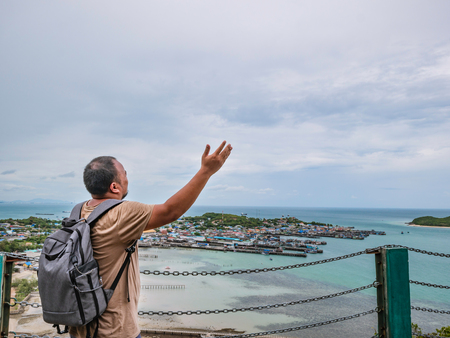 Asisn Fat Backpacker stand on top of  Khao Ma Jor Pier  with Idyllic ocean beautiful white cloud endless horizon and Fishman townscape in vacation time,chonburi thailand,holiday conceptの写真素材