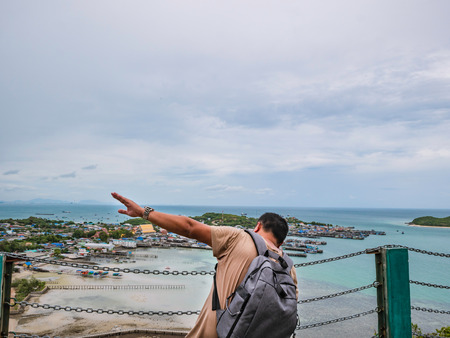 Asisn Fat Backpacker stand on top of  Khao Ma Jor Pier  with Idyllic ocean beautiful white cloud endless horizon and Fishman townscape in vacation time,chonburi thailand,holiday conceptの写真素材