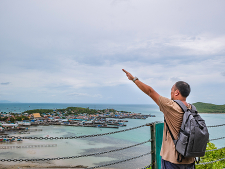 Asisn Fat Backpacker stand on top of  Khao Ma Jor Pier  with Idyllic ocean beautiful white cloud endless horizon and Fishman townscape in vacation time,chonburi thailand,holiday conceptの写真素材