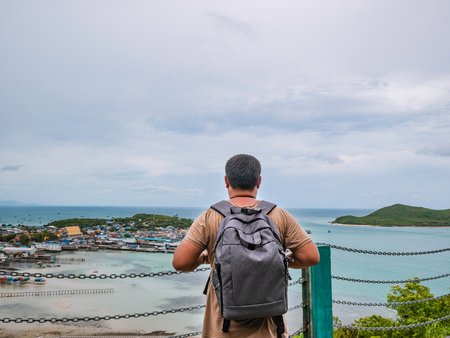 Asisn Fat Backpacker stand on top of  Khao Ma Jor Pier  with Idyllic ocean beautiful white cloud endless horizon and Fishman townscape in vacation time,chonburi thailand,holiday conceptの写真素材