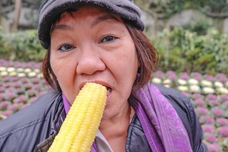 Happy old asian women eat tasty corn with delicious face in  xihu lake park hangzhou china in winter seasonの写真素材