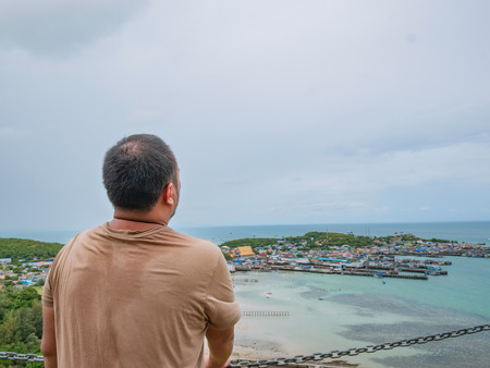 Asisn Fat Traveler stand on top of  Khao Ma Jor Pier  with Idyllic ocean beautiful white cloud endless horizon and Fishman townscape in vacation time,chonburi thailand,holiday conceptの写真素材