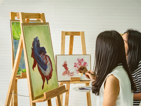 Two young asian woman artist dawning while useing ideas to think and create the best artwork together in watercolor class,fish conceptの写真素材