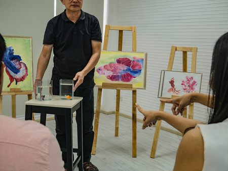 senior adult artist teacher teaching his student in the class room,fish and art drawing conceptの写真素材