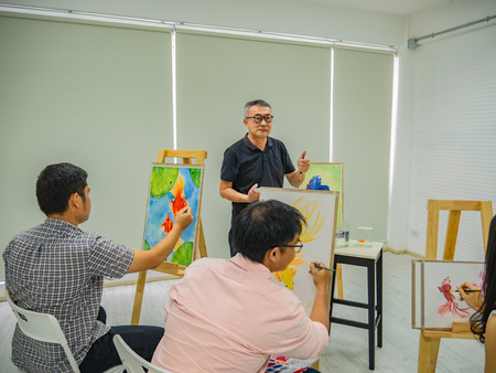 senior adult artist teacher teaching in the class room,fish and art drawing conceptの写真素材