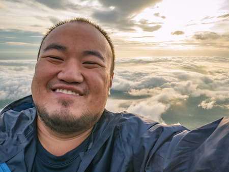 Asian Traveler Take a Selfie with Beautiful Sunrise Sky on the mountainの写真素材