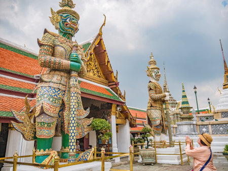 Senior asian women make a Thai greeting Pose to Giant in wat phrakaew temple in bangkok City...