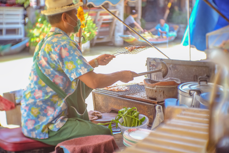Bangkok, Thailand - 21 June 2017 : Unacquainted Thai Chef selling Grilled Pork neck on the Boat in Pattaya Floating Market.Chonburi Thailand Travel.のeditorial素材