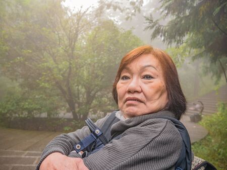 Portrait Senior asian women Wearing the hat on Zhangjiajie National Forest Park in Wulingyuan District Zhangjiajie City China in the Foggy dayの写真素材