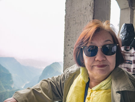 Portrait photo of beautiful asian senior women with beautiful view on Tianmen mountain and clear Sky in zhangjiajie city China.Tianmen mountain the travel destination of Hunan zhangjiajie city Chinaのeditorial素材