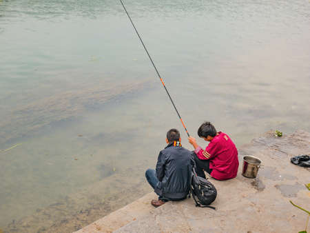 fenghuang,Hunan/China-16 October 2018:Unacquainted Chinese local people fishing in the river of fenghuang old town .phoenix ancient town or Fenghuang County is a county of Hunan Province, Chinaのeditorial素材