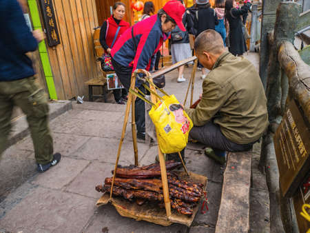 fenghuang,Hunan/China-16 October 2018:Unacquainted Chinese local people Selling Larou of smoked pork in  fenghuang old town .phoenix ancient town or Fenghuang County is a county of Hunan Province, Chinaのeditorial素材