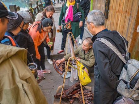 fenghuang,Hunan/China-16 October 2018:Unacquainted Chinese local people Selling Larou of smoked pork in  fenghuang old town .phoenix ancient town or Fenghuang County is a county of Hunan Province, Chinaのeditorial素材