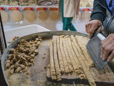 Cutting Sweet Peanuts Stick with clever knife in souvenir shop of  fenghuang old townの写真素材
