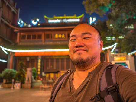 Portrail photo of asian man traveler in Huogongdian Food garden entrance Gate in Changsha city China.changsha is the capital and most populous city of Hunan province in chinaの写真素材
