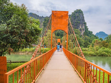 Vangvieng/lao-10 Dec 2017:Unacquainted tourist walking on Suspension bridge cross Nam Song River  at Tham Chang cave Vangvieng City Laos.Vangvieng City The famous holiday destination town in Lao.のeditorial素材