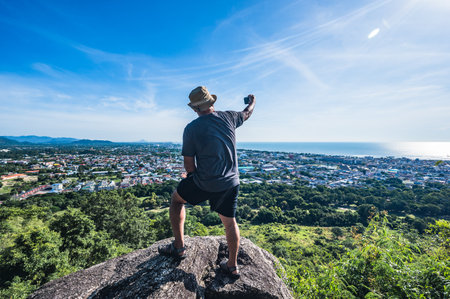 Asian fat man stand on the rock and take photo at Khao hin lek fai view point.Khao Hin Lek Fai is a place to see a spectacular view of the entire town.Also know as khao radar in local people.の写真素材