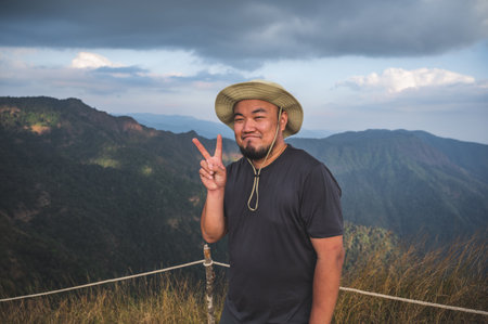 Asian fat man with beautiful view of khao San nok wua mountain kanchanaburi.Khao San Nok Wua is the highest mountain in Khao Laem National Park. It is 1767 meters above sea level.の写真素材