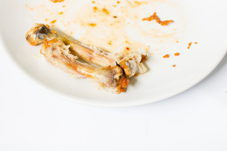 close up of chicken  bone on the white dish with with waste food  isolate background , waste food , chicken bone isolated white , copy space , with sweet sauceの写真素材