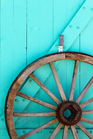 Old wooden wagon wheel against blue door, New Mexico の写真素材