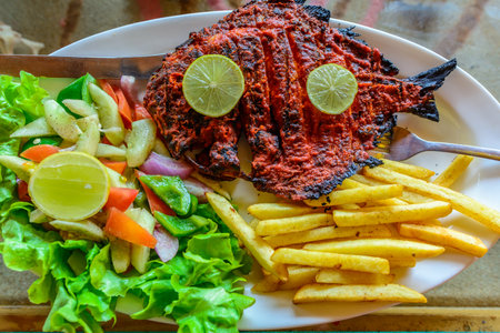 Spicy grilled fish served with french fries and saladの写真素材