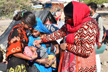 Beawar, Rajasthan, India, Feb. 01, 2021: An Anganwadi health worker administers polio vaccine drops to a child at a slum area during Pulse Polio eradication program in Beawar. Photo: Sumit Saraswatのeditorial素材