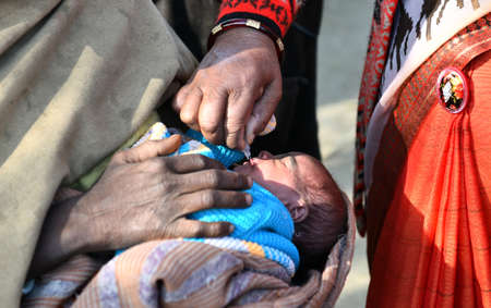 Beawar, Rajasthan, India, Feb. 01, 2021: An Anganwadi health worker administers polio drops to a newborn baby at a slum area during Pulse Polio eradication program in Beawar. Photo: Sumit Saraswatのeditorial素材