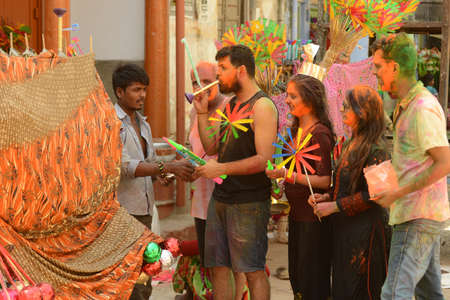 Beawar, Rajasthan, India, March 2, 2018: Indian family buys toys from a street vendor as they celebrate Holi, the spring festival of colours, in Beawar. Photo: Sumit Saraswatのeditorial素材