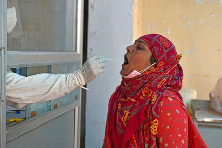 Beawar, Rajasthan, India, May 10, 2021: A health worker collects swab sample from a village woman at a COVID-19 testing lab during second wave of coronavirus epidemic, in Beawar. Photo: Sumit Saraswatのeditorial素材