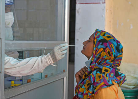 Beawar, Rajasthan, India, May 10, 2021: A health worker collects nasal swab sample from a woman at a COVID-19 testing lab during second wave of coronavirus epidemic, in Beawar. Photo: Sumit Saraswatのeditorial素材