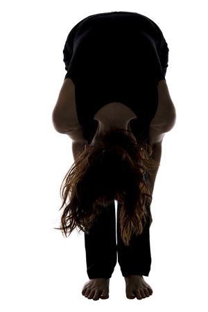 Woman is doing standing forward bend pose.の写真素材