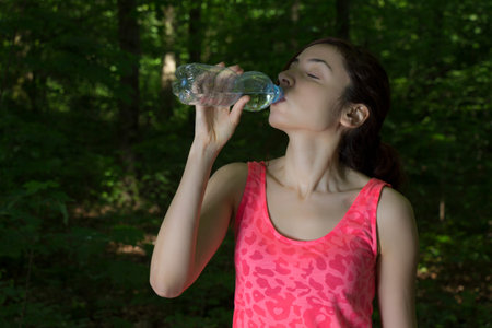 Young sporty woman is drinking water during a break.