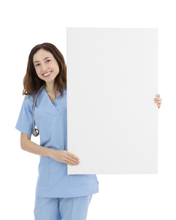 Smiling friendly female doctor or nurse showing a blank white billboardの写真素材