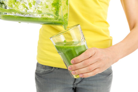 Pouring green smoothie into a glassの写真素材