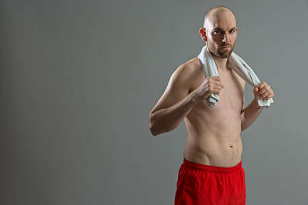Fit caucasian athlete man taking a break on grey background.の写真素材
