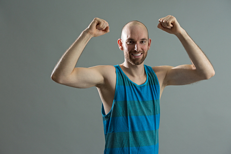 Caucasian fitness man cheering on grey background.の写真素材