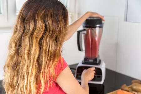 Woman making fruit smoothie with a smoothie machineの写真素材
