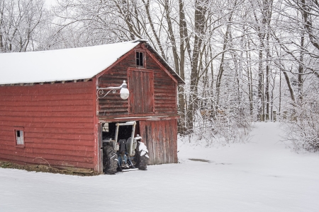 A Farm tractor pokes out of the barn after an early morning snowfall in Rotterdam, New Yorkのeditorial素材