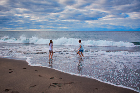 Two sisters play with the waves on the Atlantic in the Azoresの写真素材